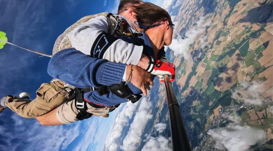 Vue au grand angle montrant le paysage et les parachutistes juste après la sortie