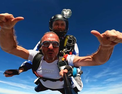 Sauteur bras écartés et pouces levés en chute libre lors d'un baptême de parachute à Tours