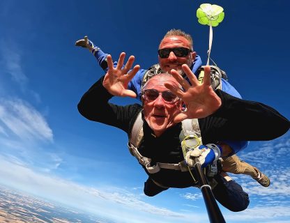 Sauteur aux cheveux gris, mains ouvertes, en chute libre au-dessus des champs de Touraine