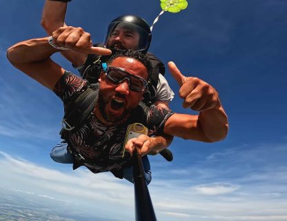 Sauteur pouce levé en chute libre dans un ciel bleu lors d'un saut tandem
