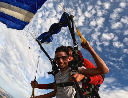 Sauteur souriant sous la voile d'un parachute tandem, ciel bleu et nuages au-dessus de la Touraine