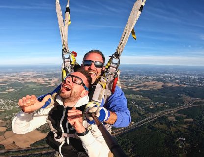 Sauteur pouce levé sous la voile d'un parachute tandem, vue sur la campagne au sud de Tours