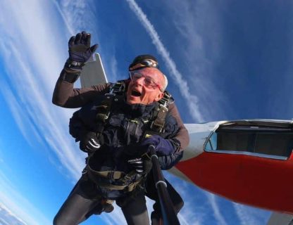 Silhouette d'un parachutiste effectuant un saut dans un ciel bleu azur