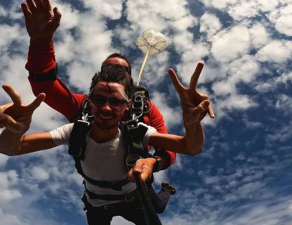 Sauteur faisant le signe de la victoire en chute libre, nuages en arrière-plan
